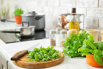 Cutting board with knife and fresh herbs on table in kitchen