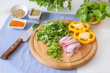 Cutting board with fresh herbs, vegetables and spices on table