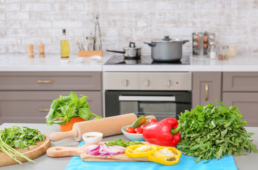 Cutting board with fresh herbs and vegetables on table in kitchen