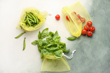 Eco bags with fresh products on light background