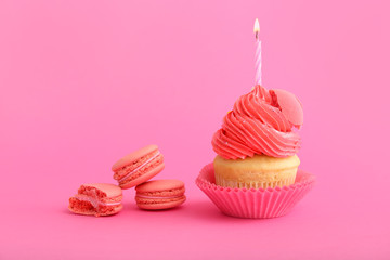 Sweet tasty Birthday cupcake with macarons on color background
