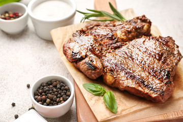 Board with tasty grilled meat on table