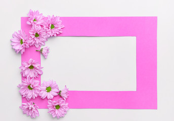 Beautiful fresh flowers and frame on light background