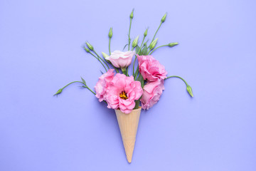 Beautiful composition with waffle cone and fresh flowers on color background