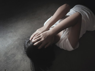 Teenage girl stop violence and rape concept laying on the floor with a grunge darkness background