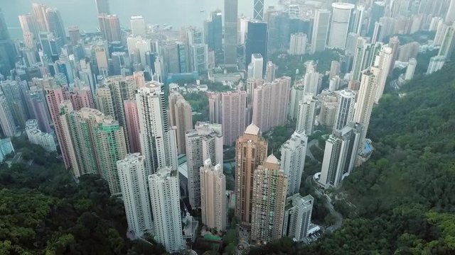 Aerial: Hong Kong City Skyscrapers from the Mountain Behind to the Harbor Ahead