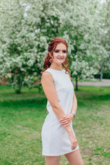 Charming woman wearing beautiful white dress under the apple tree
