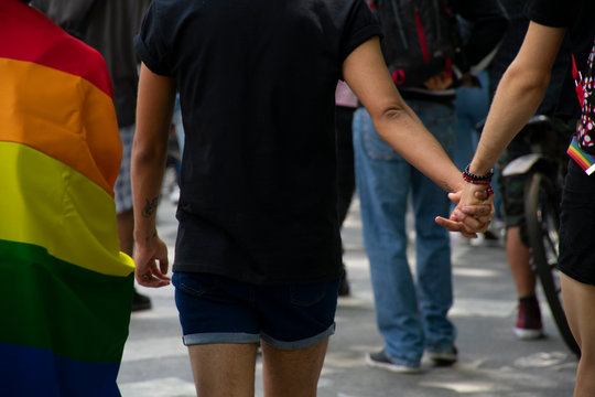 Una pareja de hombres homosexuales con las manos entrelazadas y caminando juntos