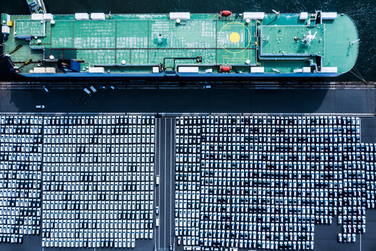 New ready to export cars in a parking lot and a car carrier from above