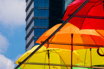 Sombrillas abiertas de colores brillantes, amarillo, anaranjado y rojo,  que adornan la calle