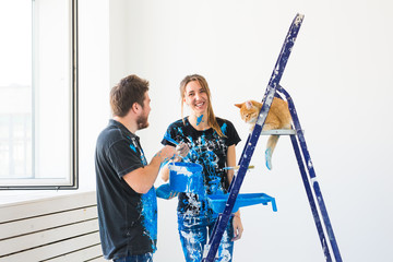 Repair, renovation, pet and love couple concept - young family with cat doing repair and painting...