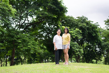 Portrait of middle aged asian woman with daughter standing at park together,Elderly health care insurance