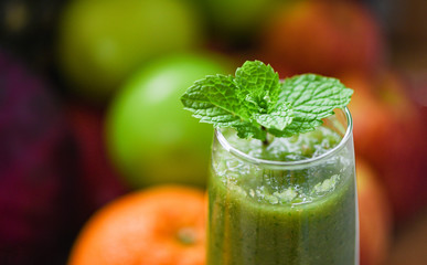 peppermint tea - green mint leaf on fresh vegetable juice smoothie and summer fruit background