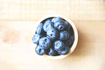 Fresh blueberries fruit in bowl on the wooden table background