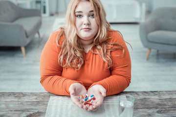 Charming overweight female person demonstrating her pills