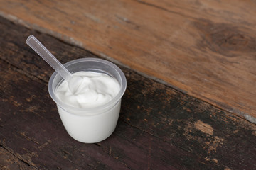 Natural homemade plain organic yogurt in cup on wood texture background