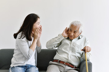 Hearing loss problem, Asian old man with hand on ear gesture trying to listen shouting woman, Aging...
