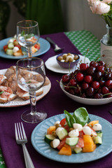 A gourmet lunch for two: a salad, fresh cherries and various appetizers.
