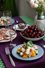 A gourmet lunch for two: a salad, fresh cherries and various appetizers.