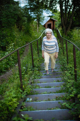 An elderly old woman walks in a summer Park.