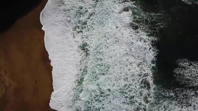 Aerial footage of the ocean waves crashing along the California beach shore.