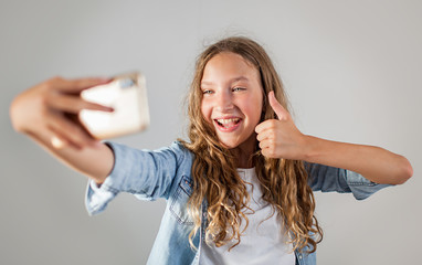 Smiling teen making selfie photo on smartphone over white background  cute girl