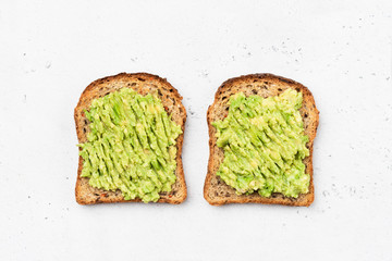 Avocado toast on whole grain sandwich bread. Table top view. Mashed avocado toasts. Concept of healthy eating, dieting, vegan vegetarian food