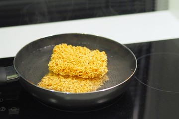 Salary man is boiling instant noodles for dinner.