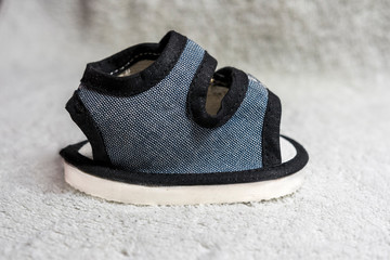 Blue, black and grey baby shoe on white textured background