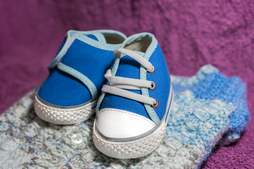 Blue baby shoes on violet textured background