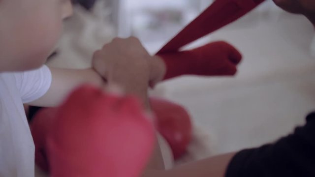 Close-up of fathers hands putting on red straps for his son, getting ready for training.