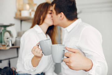 Cute couple in a kitchen. Lady in a white shirt. Pair at home