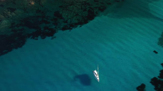 View from above, stunning aerial view of a sailing boat floating on a beautiful turquoise clear sea. Maddalena Archipelago National Park, Sardinia, Italy.