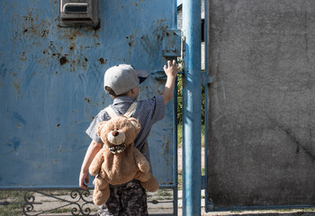 a little boy in the yard with a backpack