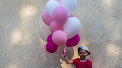 a handsome boy holds in his hand many colored balloons