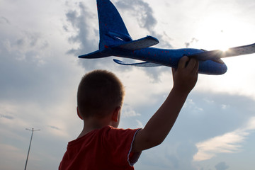 a boy playing with a airplane in the street