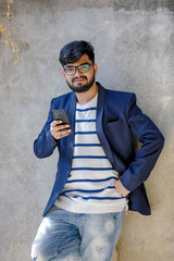 young indian man wearing suit and typing on phone at outdoor location