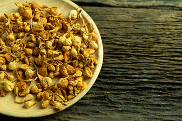 Dried cordyceps militaris in wooden dish on old wooden floors