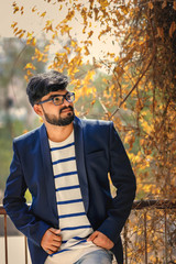 Portrait of a young Indian successful businessman wearing suit over wall background