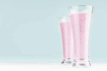 Set of two diet milk beverages with blueberry in elegant glass on pastel soft light blue background, copy space.
