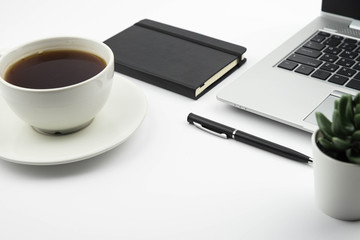 Modern office desk workspace with coffee cup, notebook, laptop and succulent with copy space on white background. Top view. Flat lay. Education, freelance and business concept