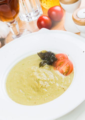 bowl of broccoli and green peas cream soup on wooden table