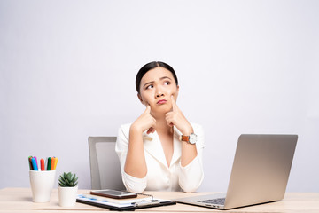 Portrait of a confused woman sitting at office isolated over background