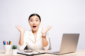 Portrait of a excited woman sitting at office isolated over background
