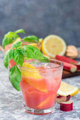 Refreshing lemonade with rhubarb, lemon, sparkling water and basil in  glass, vertical, copy space