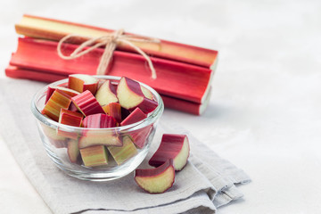 Cutted rhubarb in glass dish, whole sticks on background, horizontal, copy space