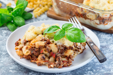 Macaroni casserole with ground beef, cheese and tomato on a plate, horizontal, closeup