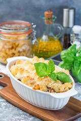 Macaroni casserole with ground beef, cheese and tomato in baking dish, vertical