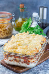 Macaroni casserole with ground beef, cheese and tomato in a glass baking dish, vertical