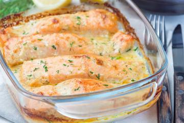 Baked in creamy sauce salmon in  glass baking dish, horizontal, closeup